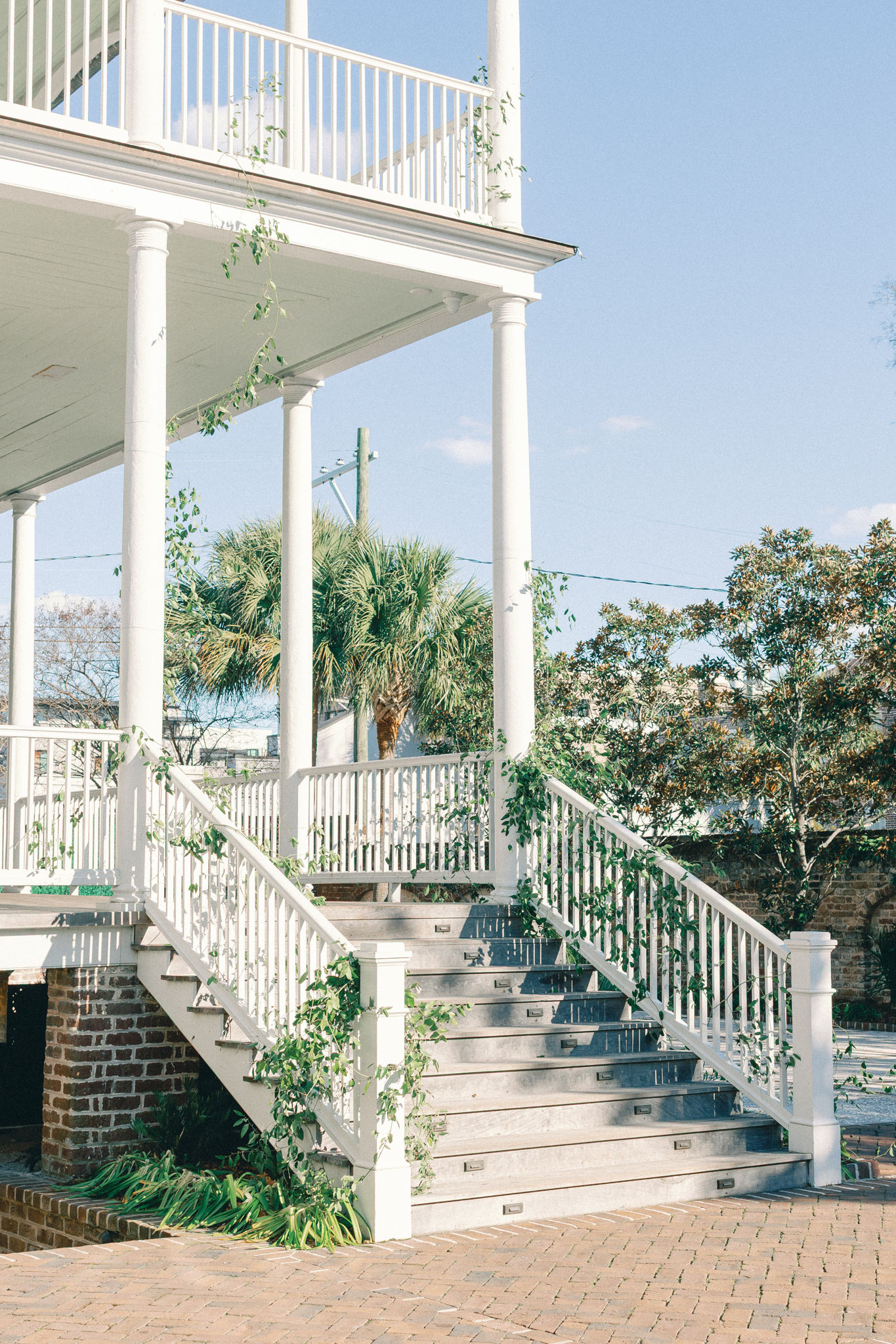 gadsden house, White double-piazza house with a curved staircase, columns and greenery on the rails — a historic Charleston wedding venue