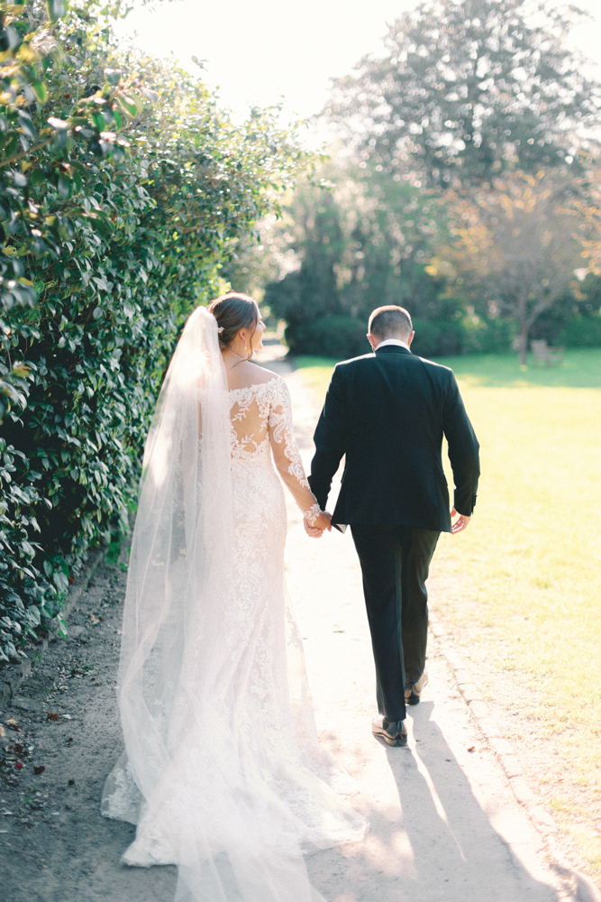 bride and groom walking through garden