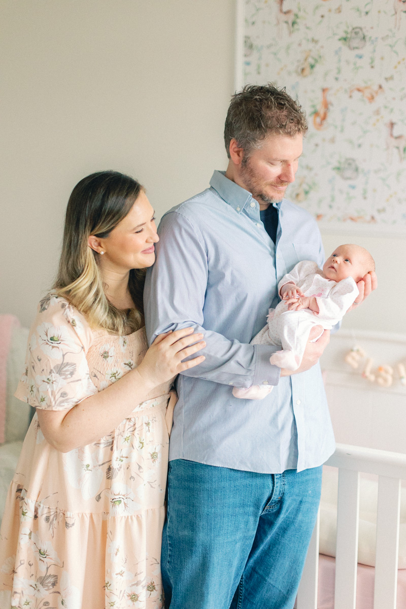 parents holding newborn in baby room