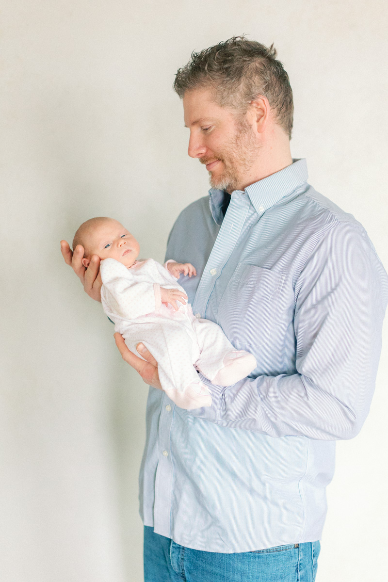 dad with newborn baby in front of fine art backdrop