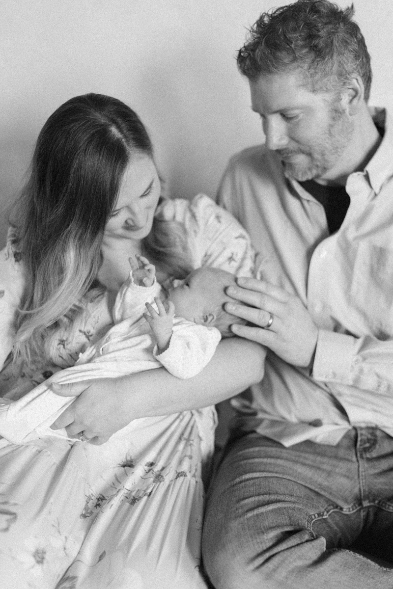 parents snuggling newborn sitting down