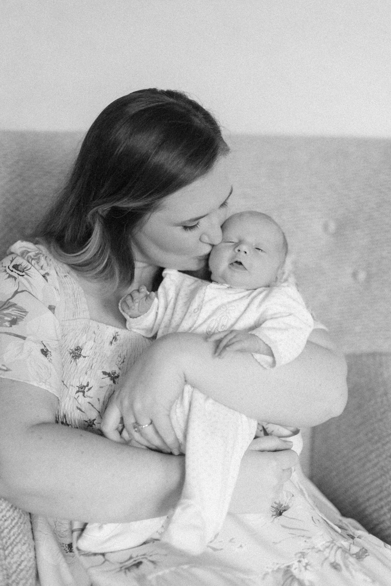 mom kissing newborn baby