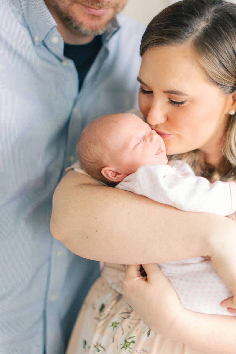 mom kissing newborn baby