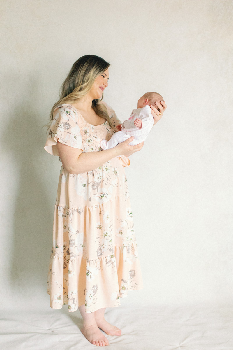 mom with newborn baby in front of fine art backdrop