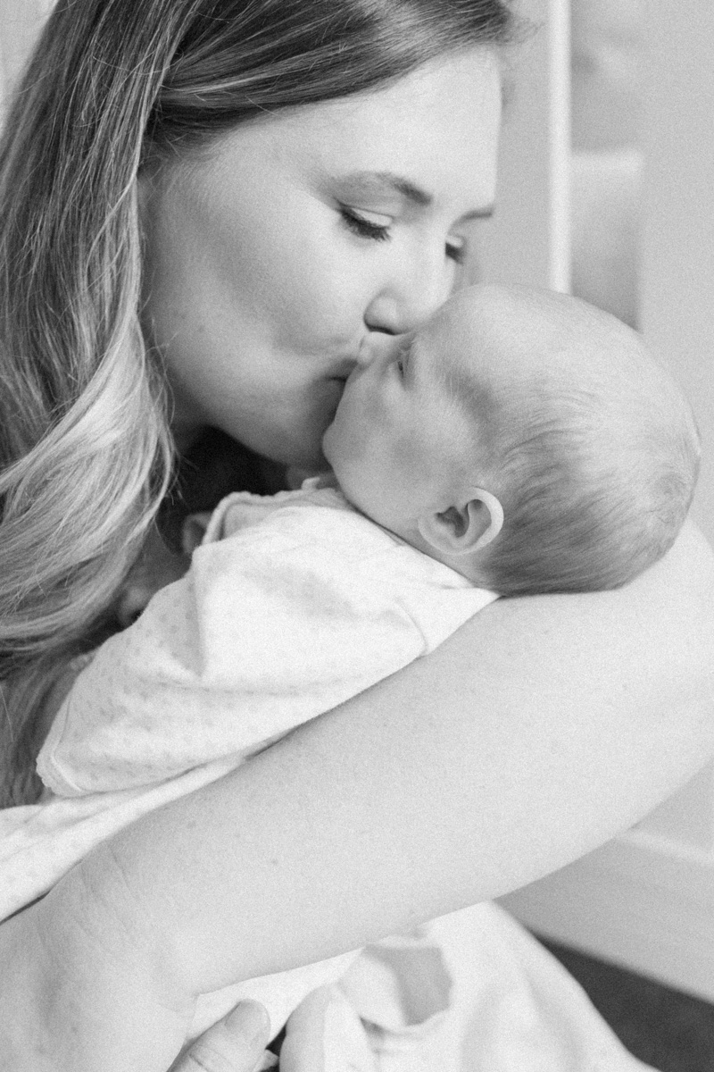 mom snuggling and kissing newborn baby