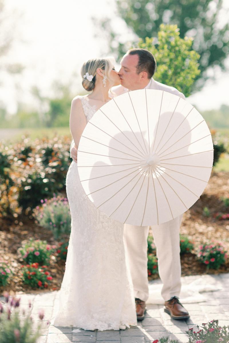 bride and groom kissing with a parasol