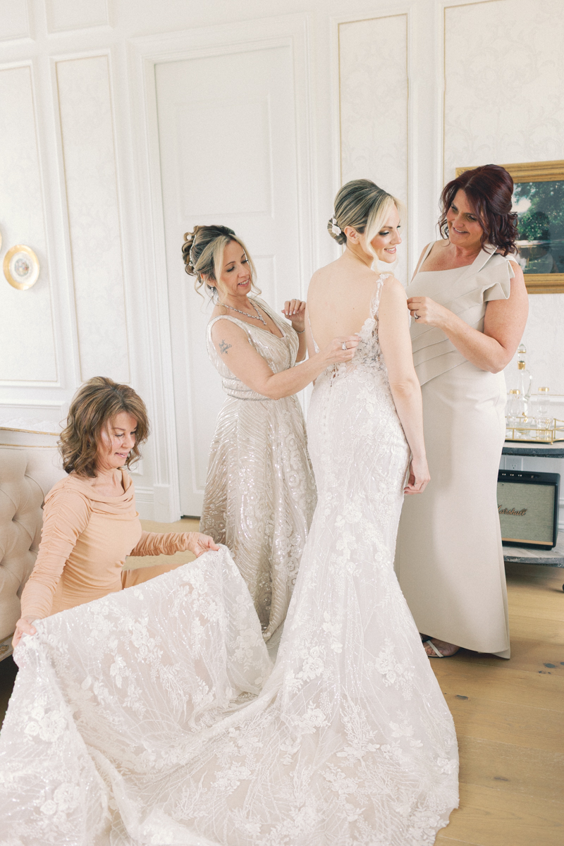 bride putting on dress with moms