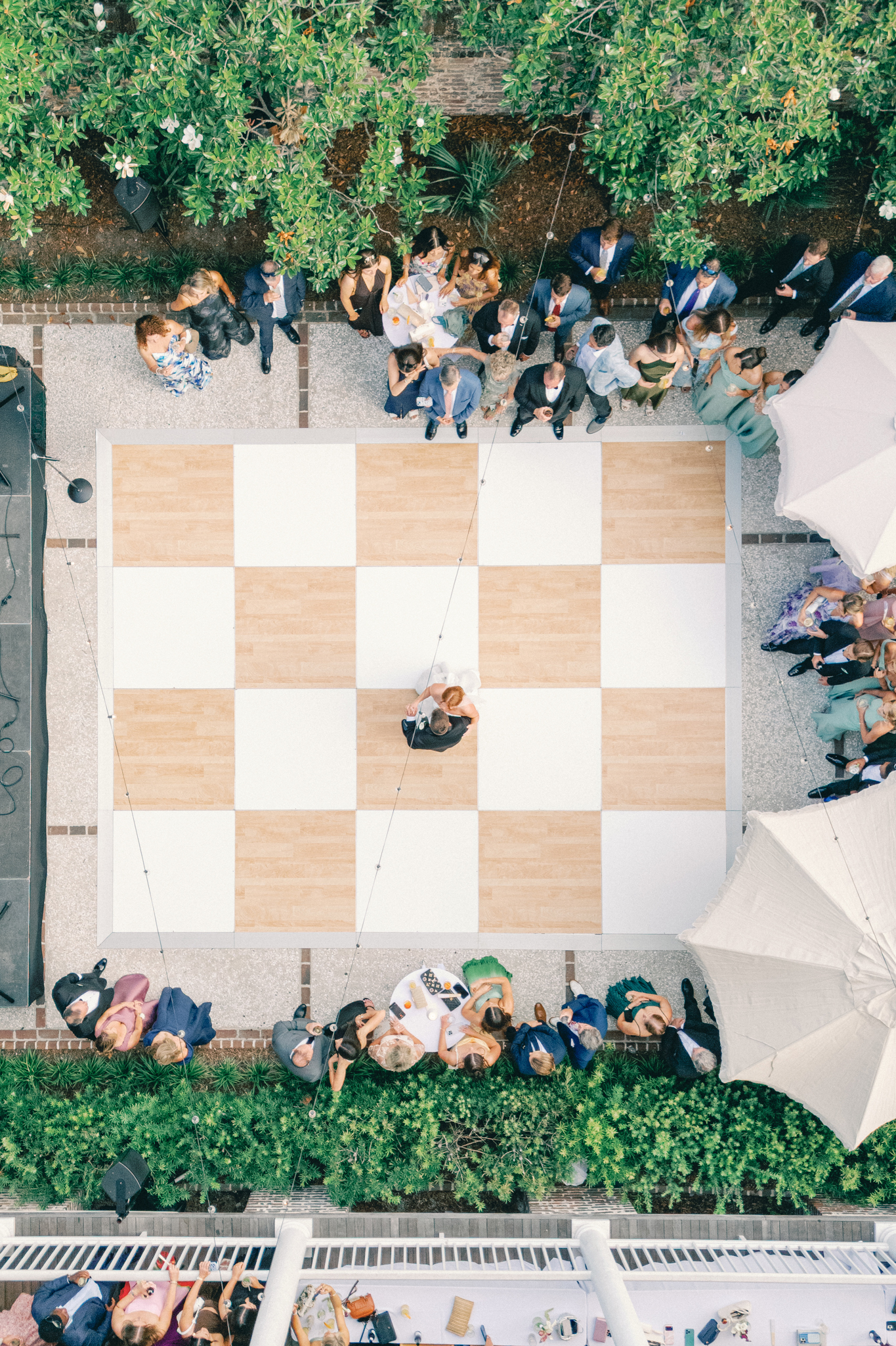 Overhead view of the couple dancing on a checkerboard floor as guests gather in the Gadsden House courtyard, a Charleston wedding venue