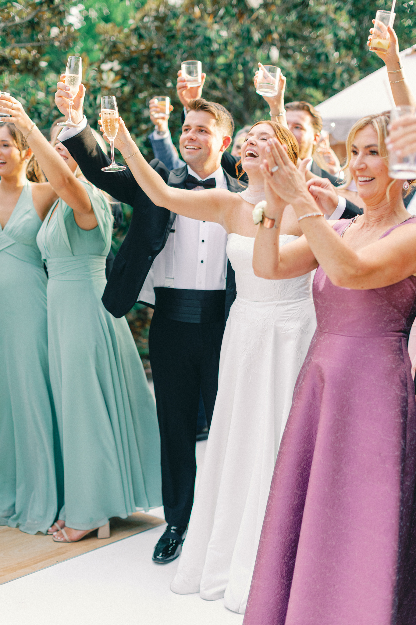 Bride, groom, and guests raise a toast with champagne, bridesmaids in sage green, at a Gadsden House wedding