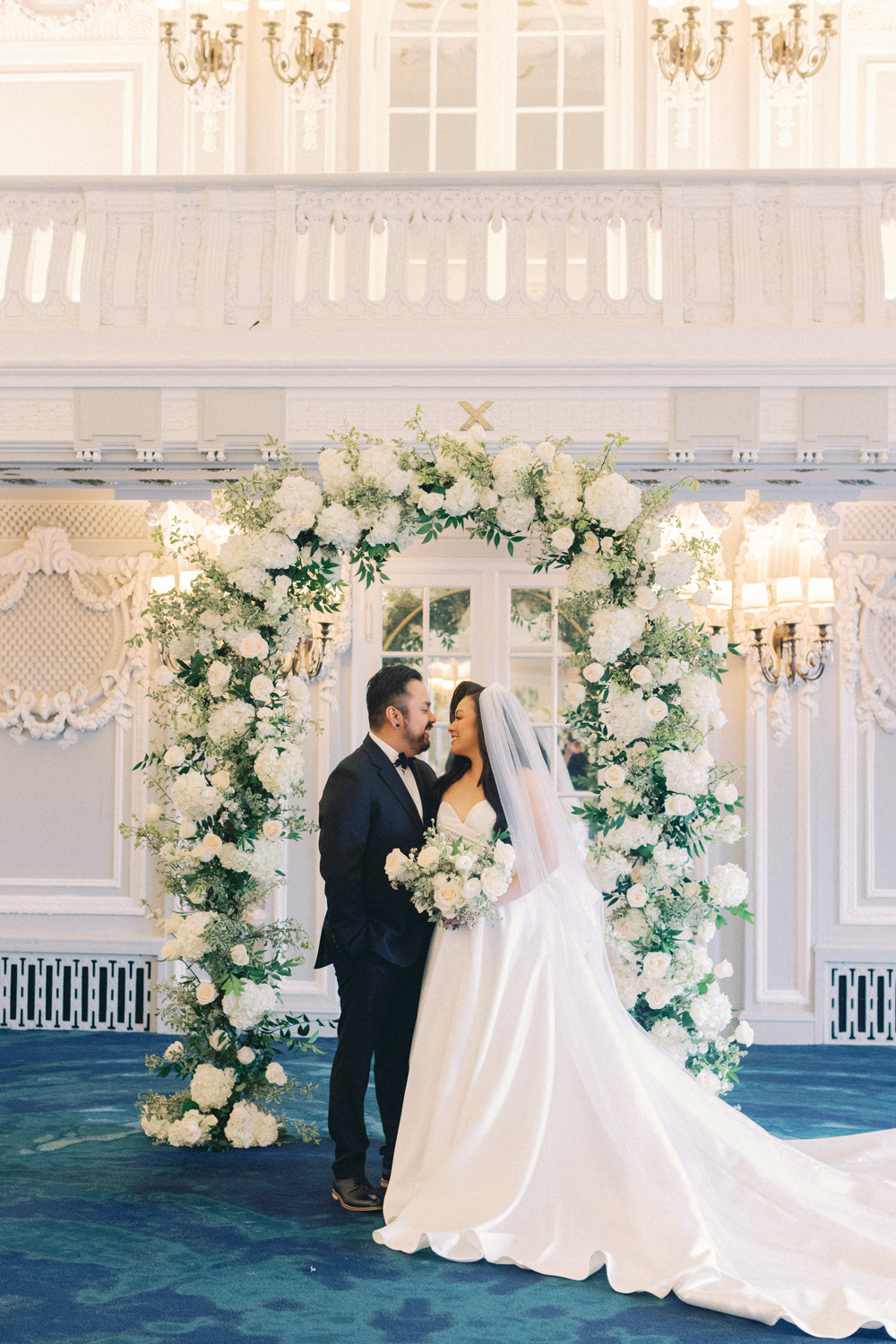 bride and groom in front of arch