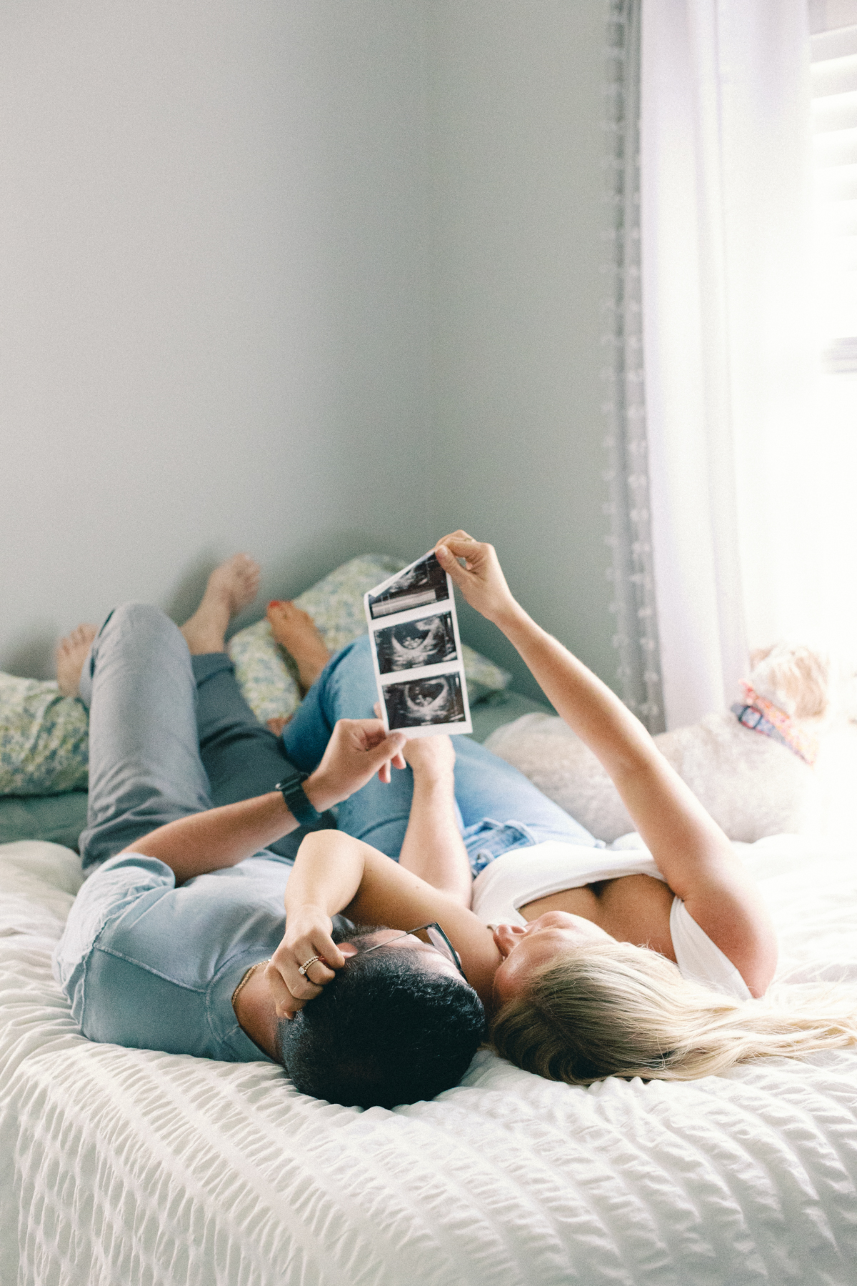 couple laying in bed looking at ultrasound picture