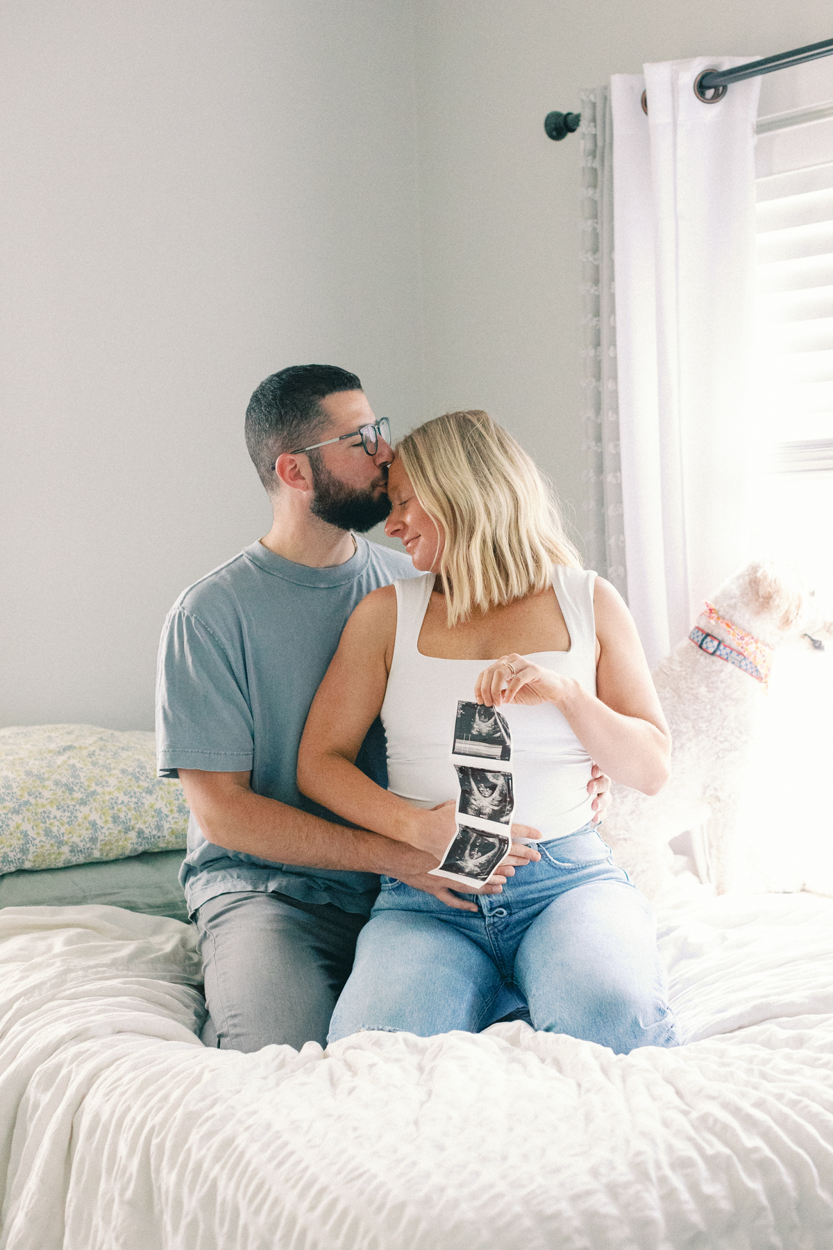 couple snuggled in bed looking at ultrasound picture