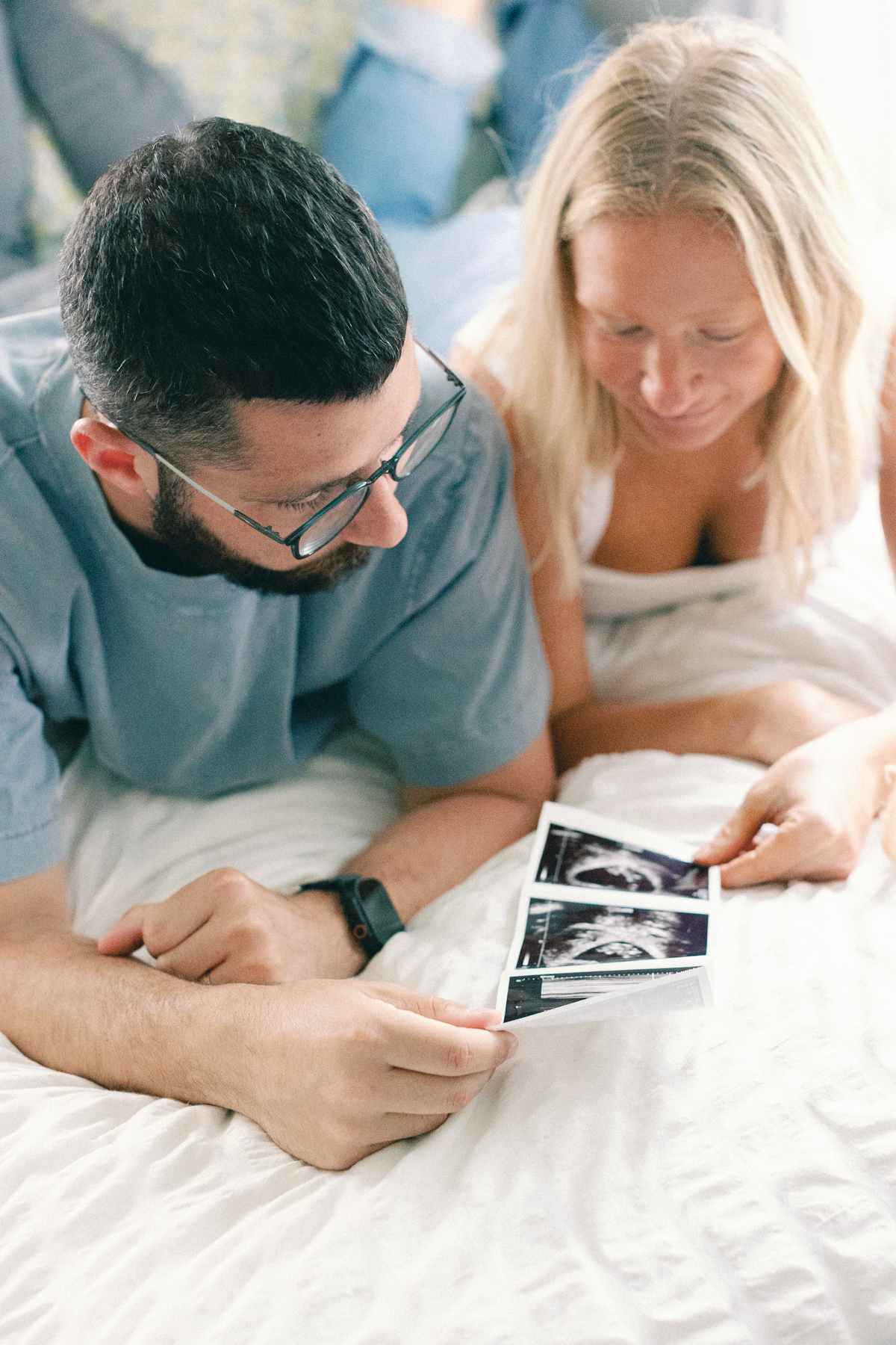 couple laying in bed looking at ultrasound picture