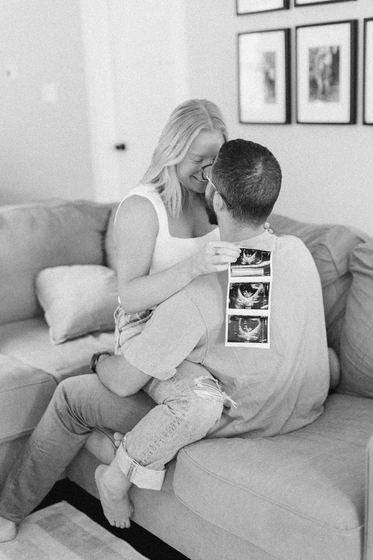 couple snuggled on couch holding ultrasound picture