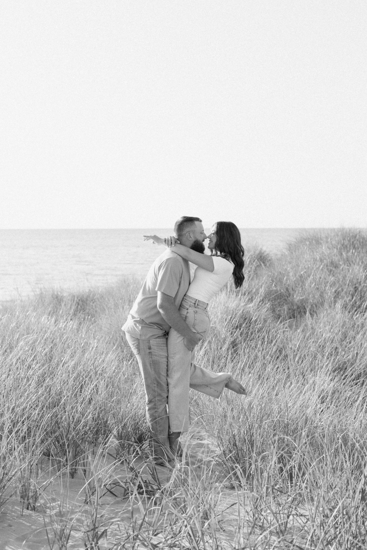 groom holding bride in field