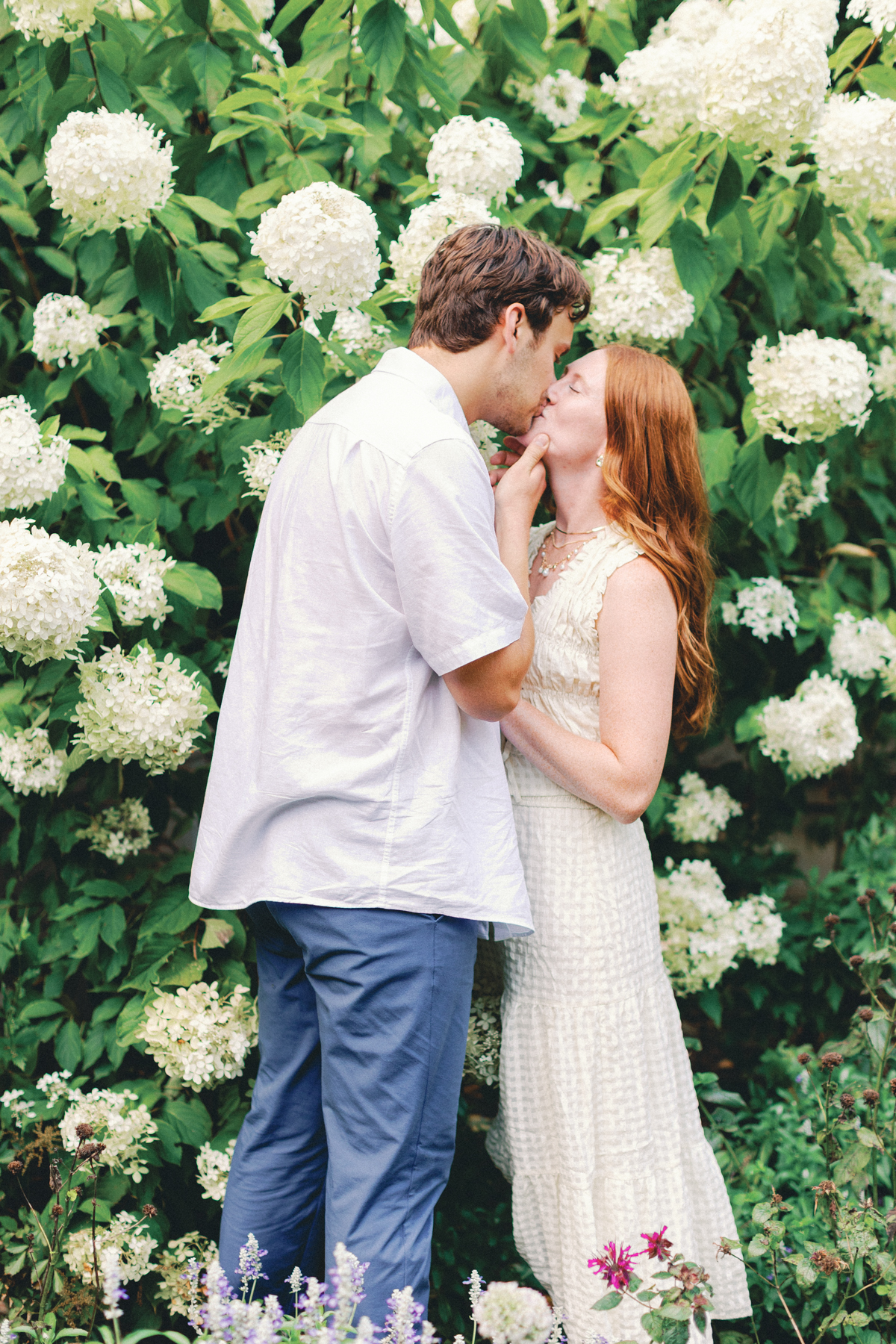  couple kissing in a hydrangea bush
