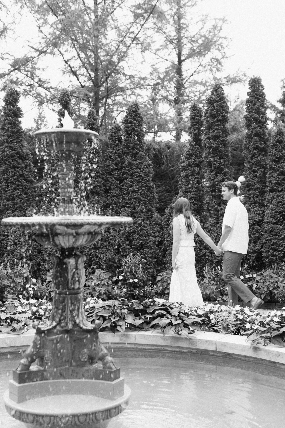  Black and white photo of couple walking in front of fountain