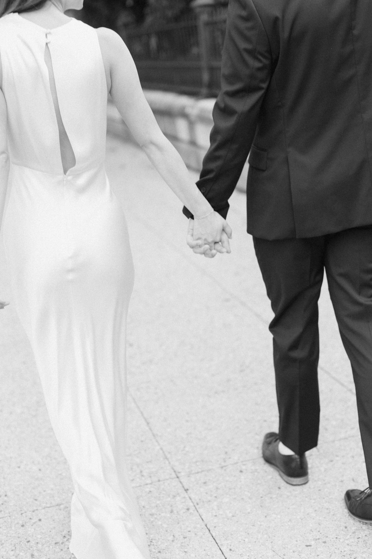 Black-and-white photo of couple hands walking away