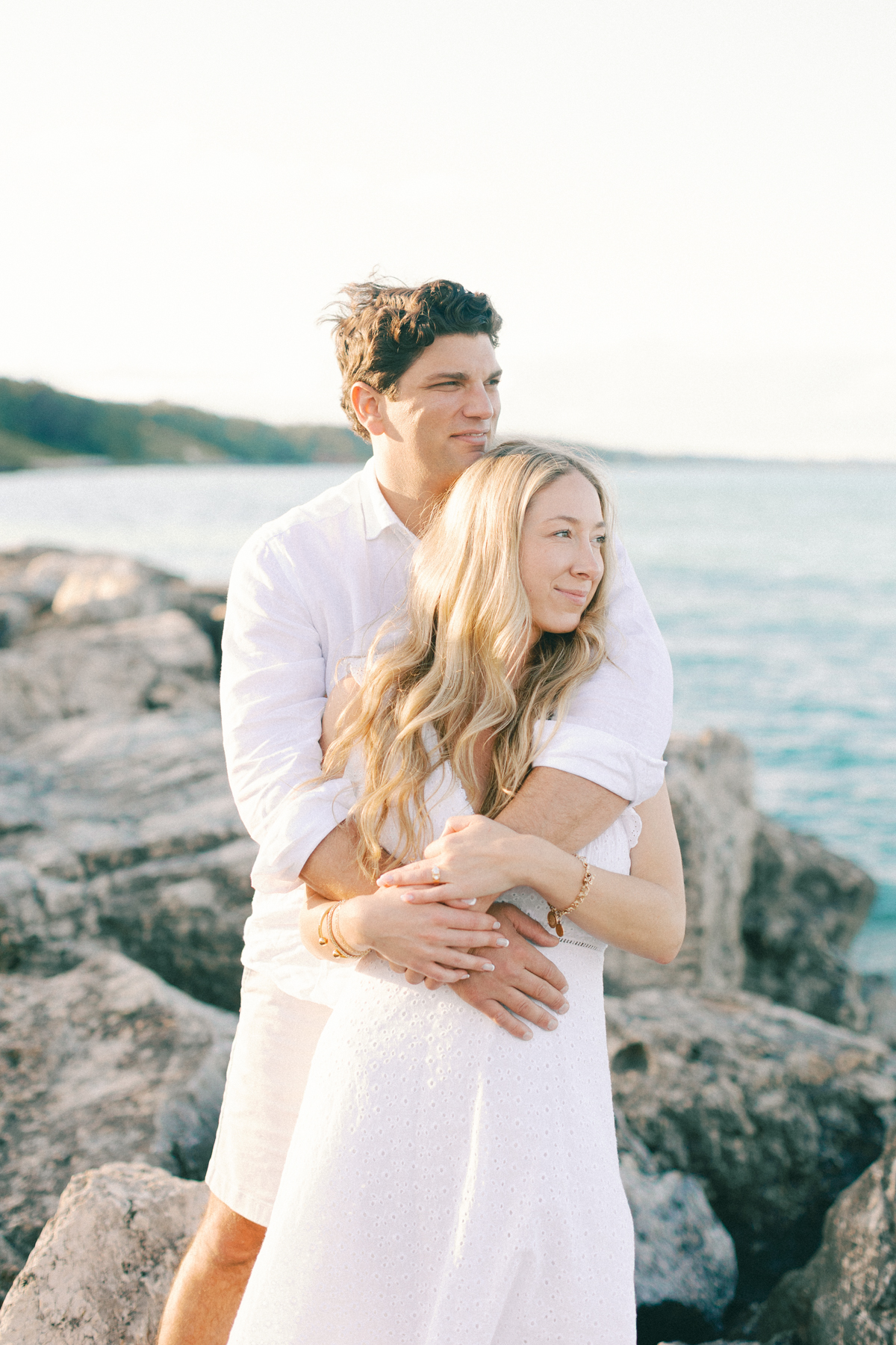 Couple cuddled on rocks looking in distance