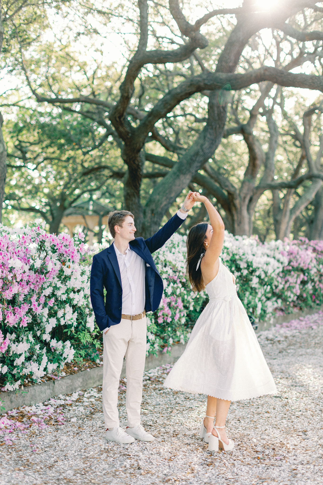 Couple dancing beneath live oaks among pink azaleas at Hampton Park during Charleston engagement pictures