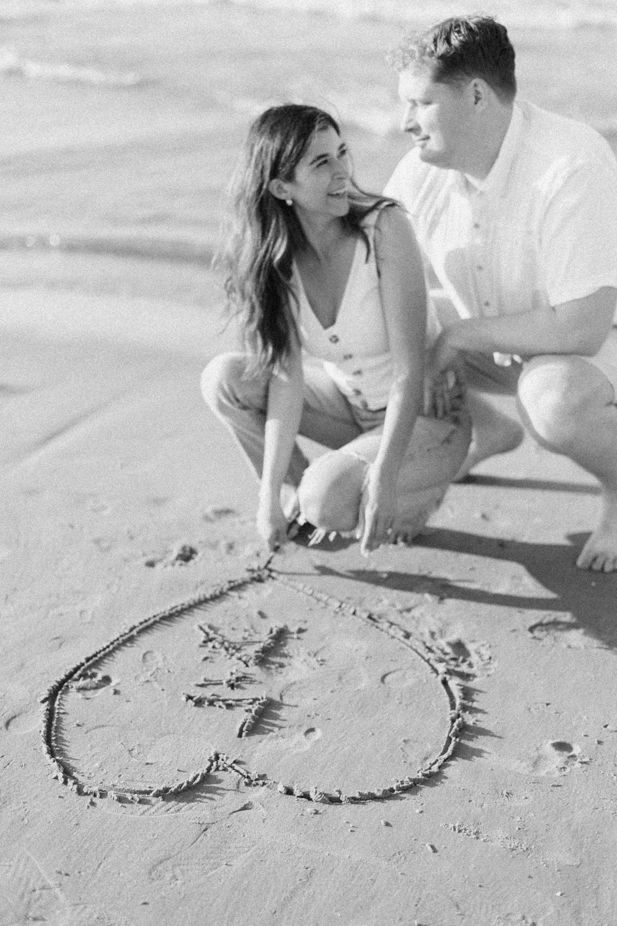 Couple drawing name in sand