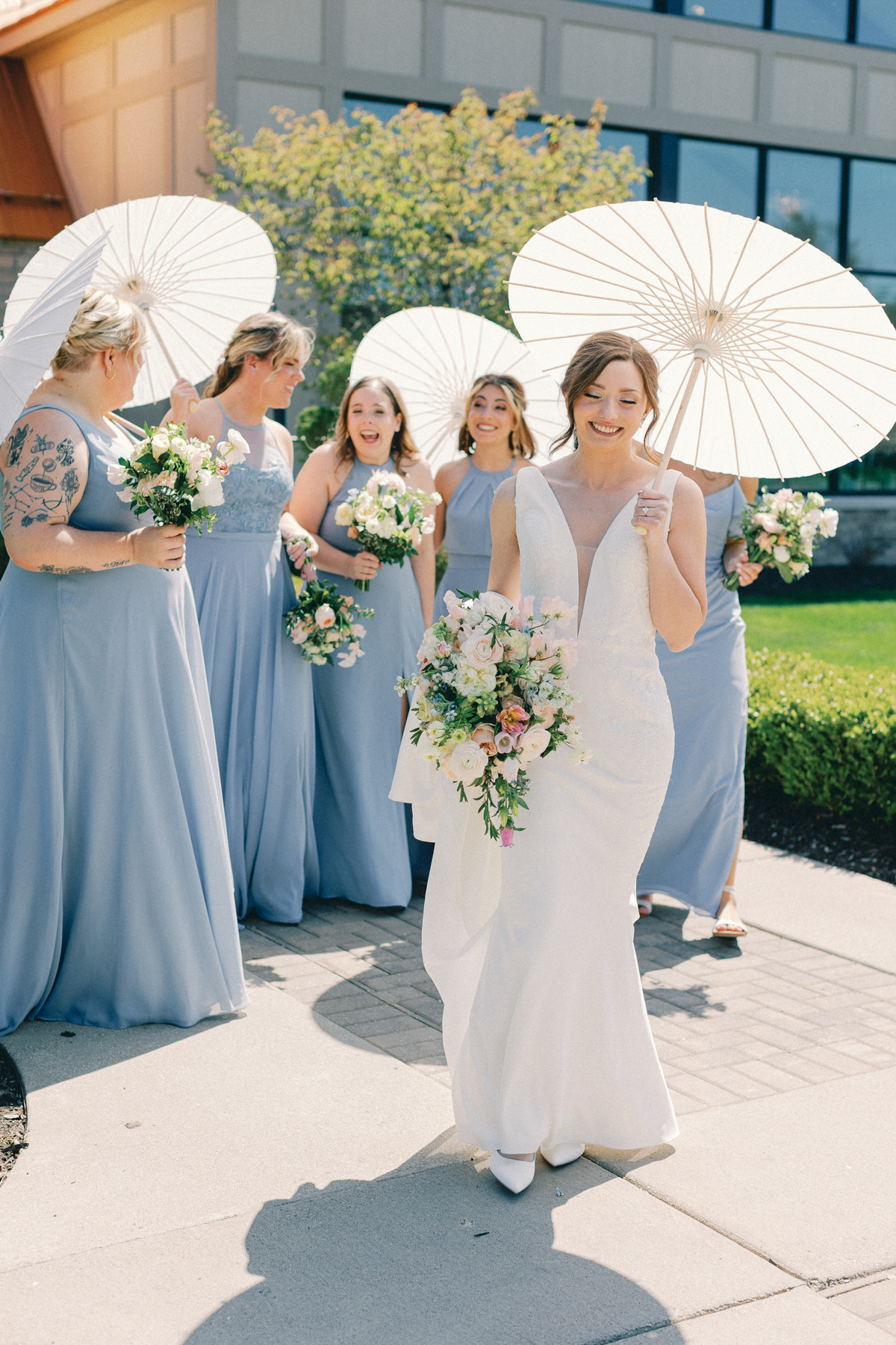 Bridesmaids walking with parasols and bouquet