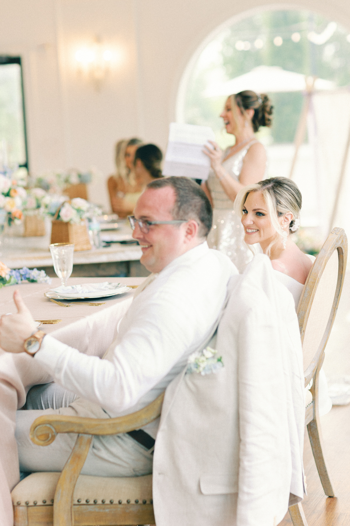 Bride and groom, laughing at speeches