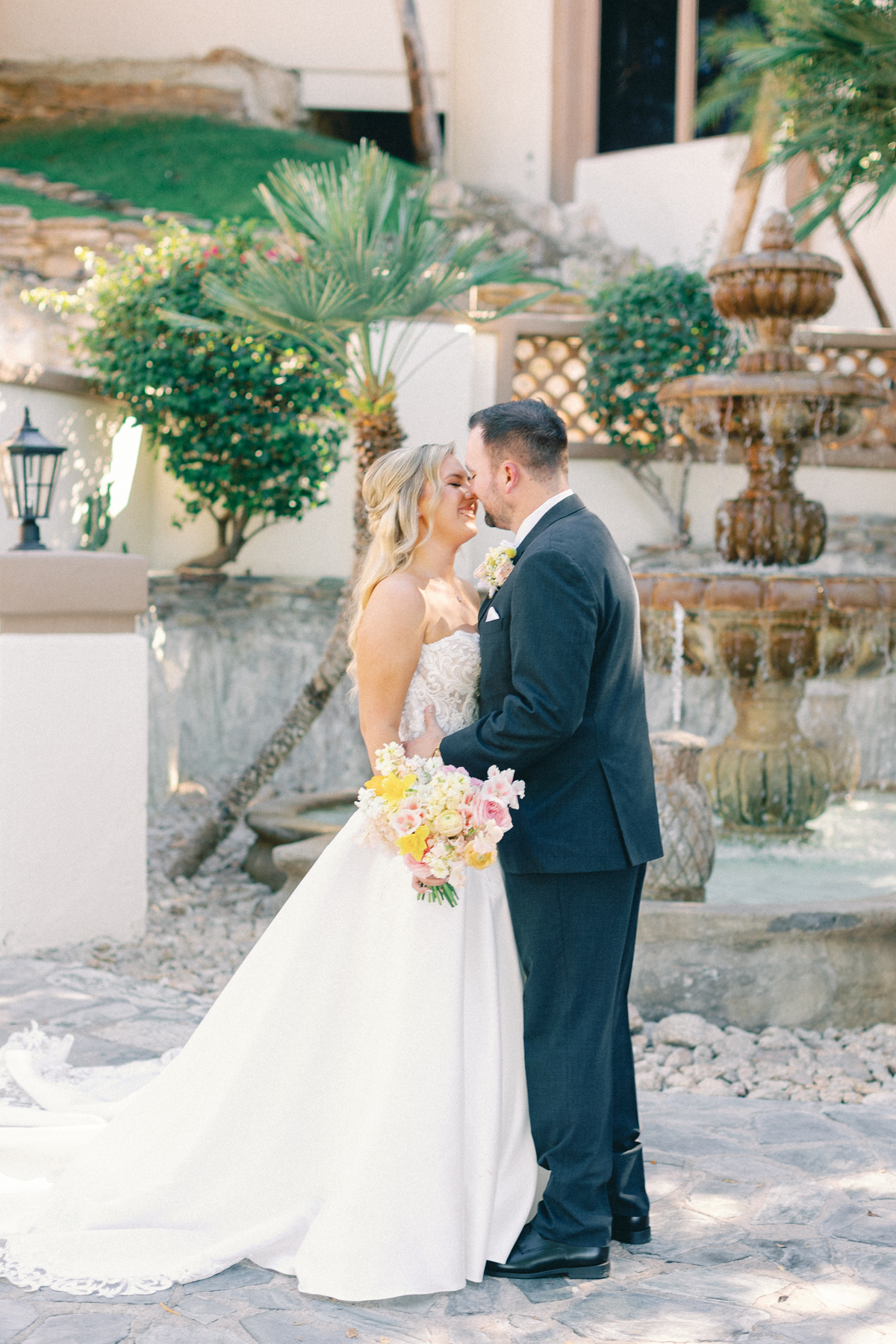 Bride and groom, kissing in front of fountain