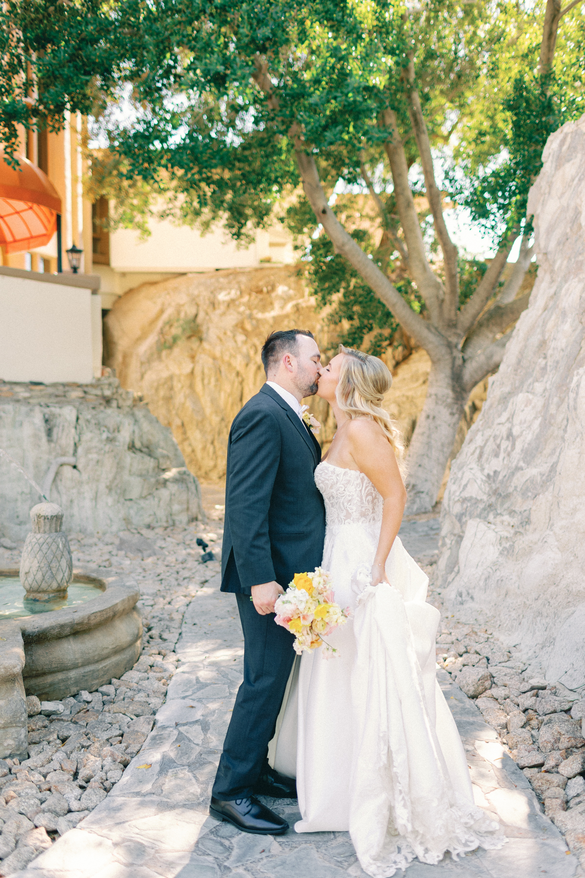 Bride and groom, kissing on path