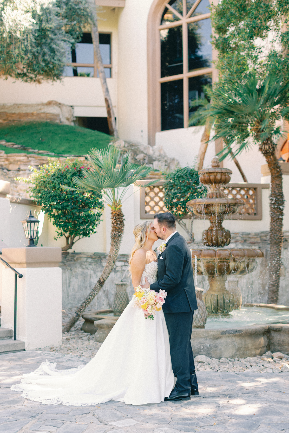 Bree and (groom) kissing in front of fountain