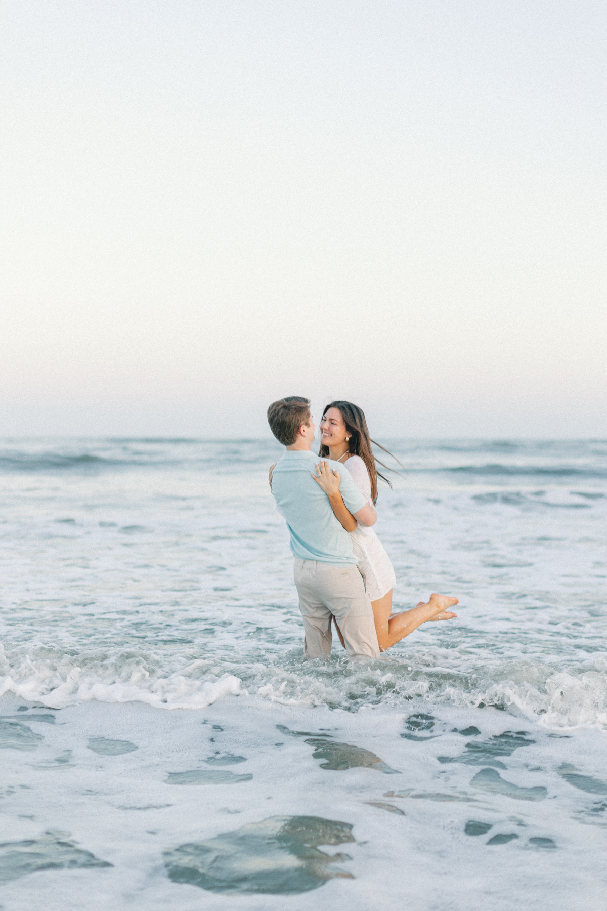 Couple twirling in water laughing