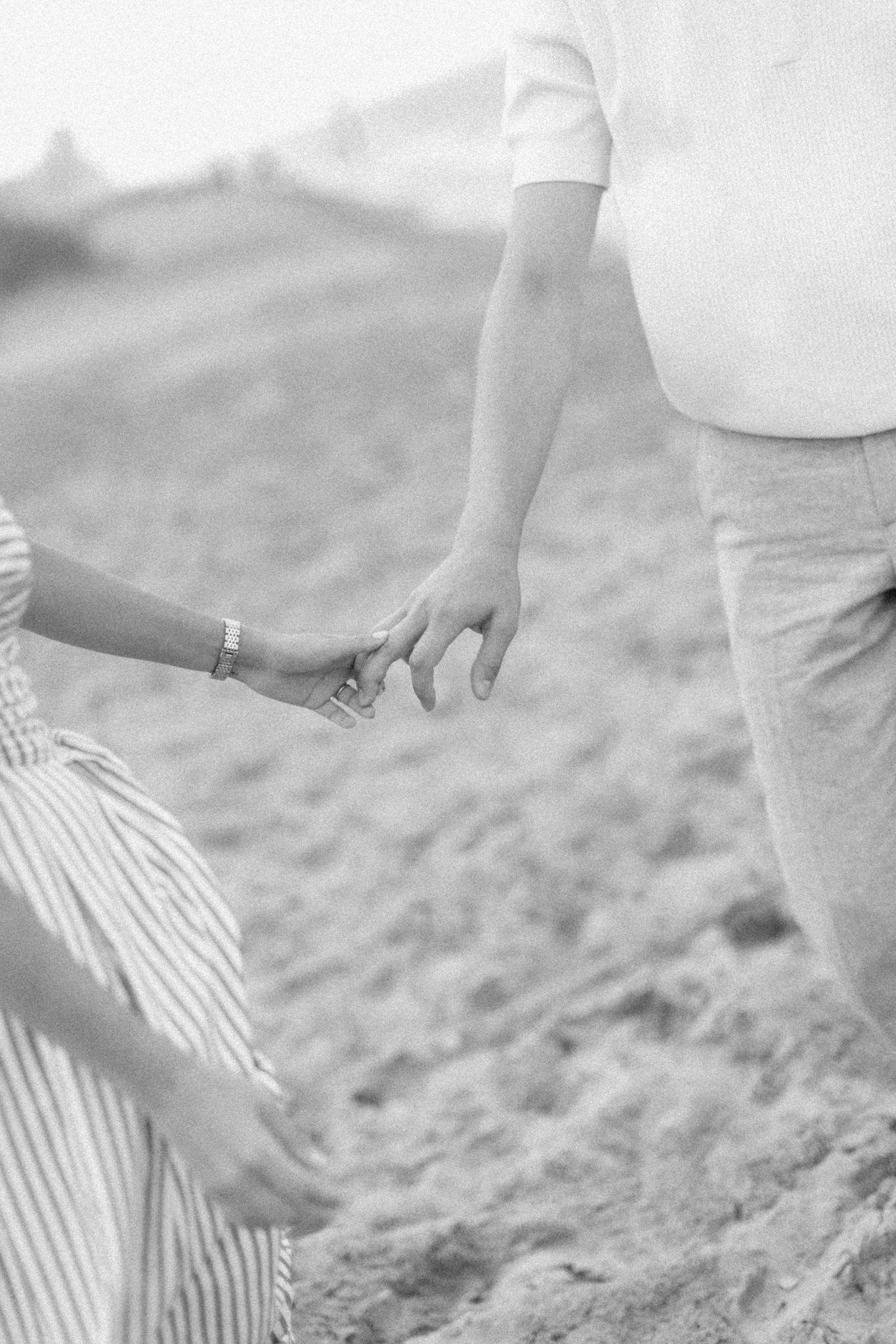 Black and white close-up of Emma and Caleb holding hands while walking, Michigan engagement photography.