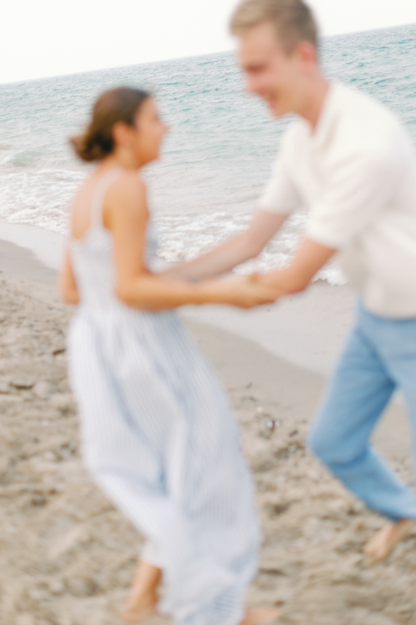 Motion-blurred moment of Emma and Caleb holding hands on the beach in Port Huron, Michigan.