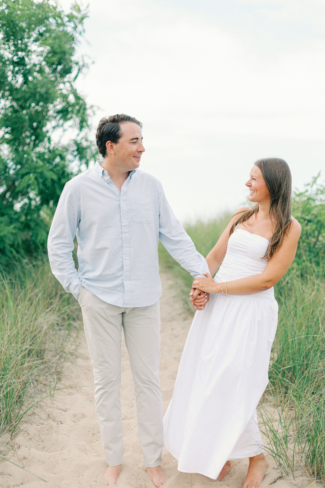 Lauren and Jason holding hands and laughing in tall dune grass