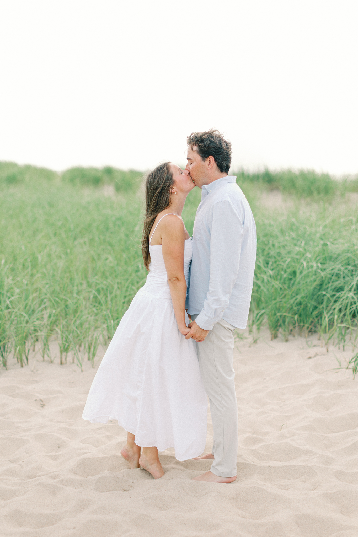 Lauren and Jason kissing on the sand surrounded by dune grass