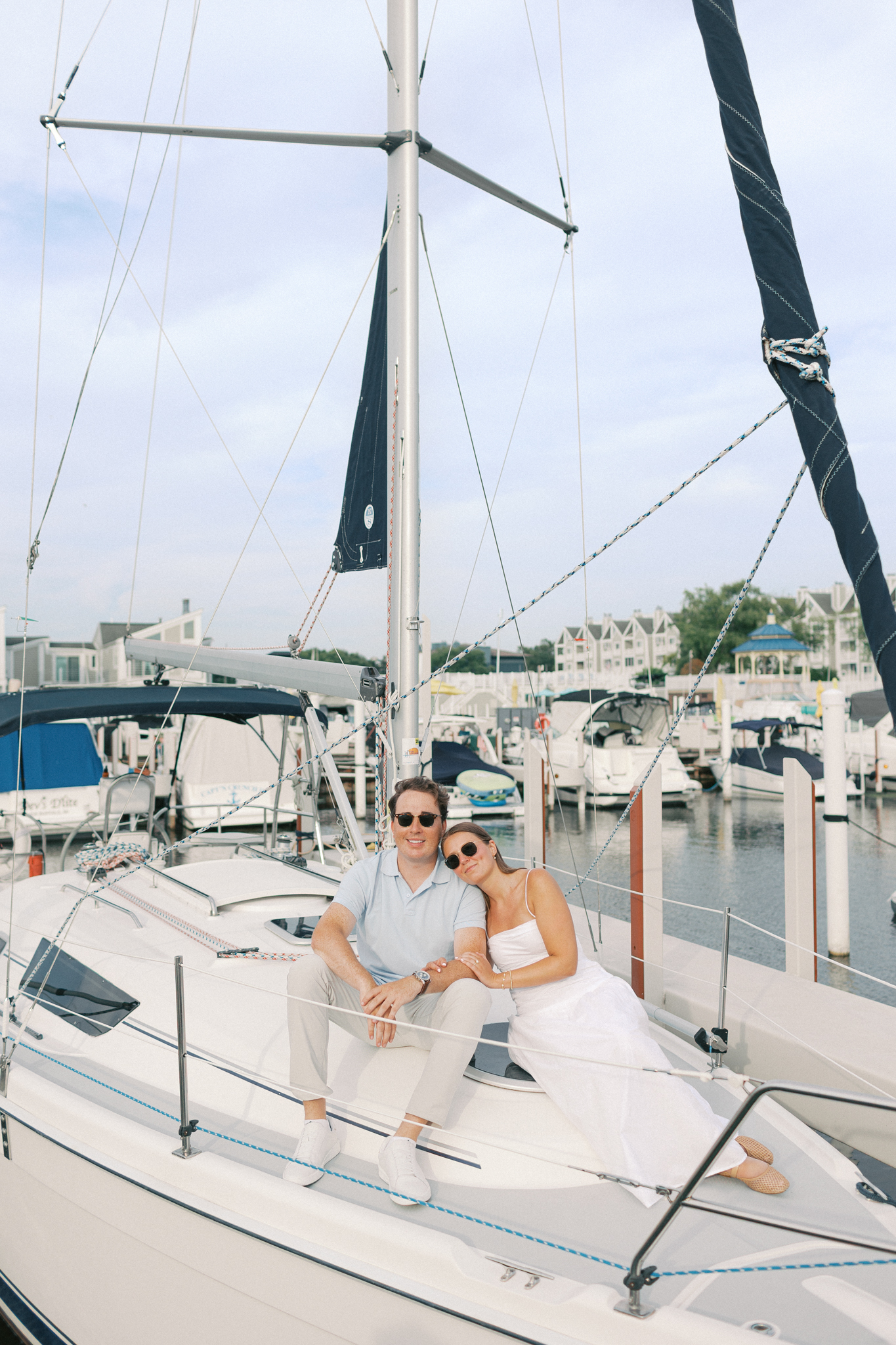 Lauren and Jason sitting together on the bow of a sailboat in the marina for their Lake Michigan sailboat engagement photos