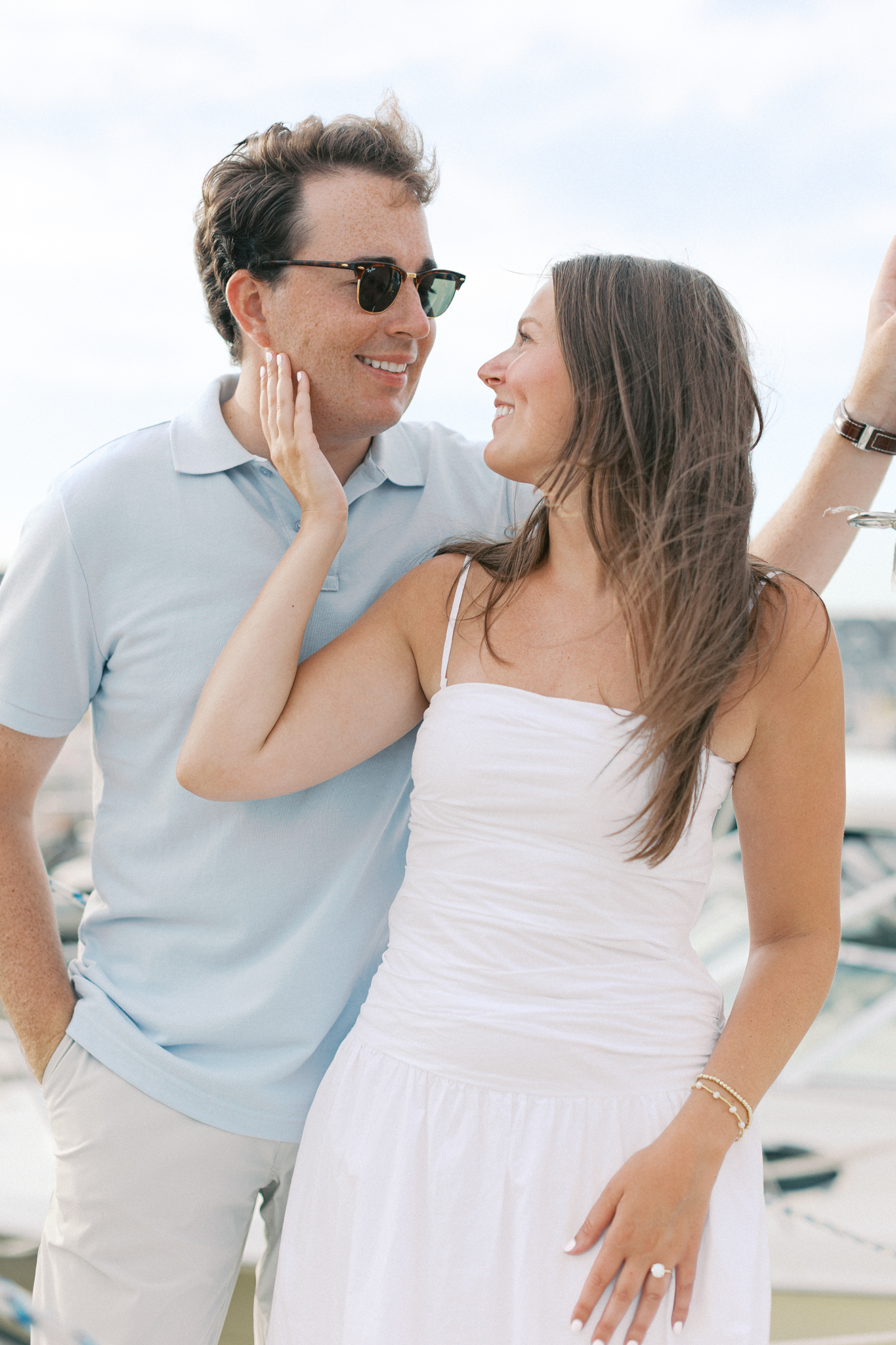 Jason in sunglasses smiling as Lauren touches his face at the marina