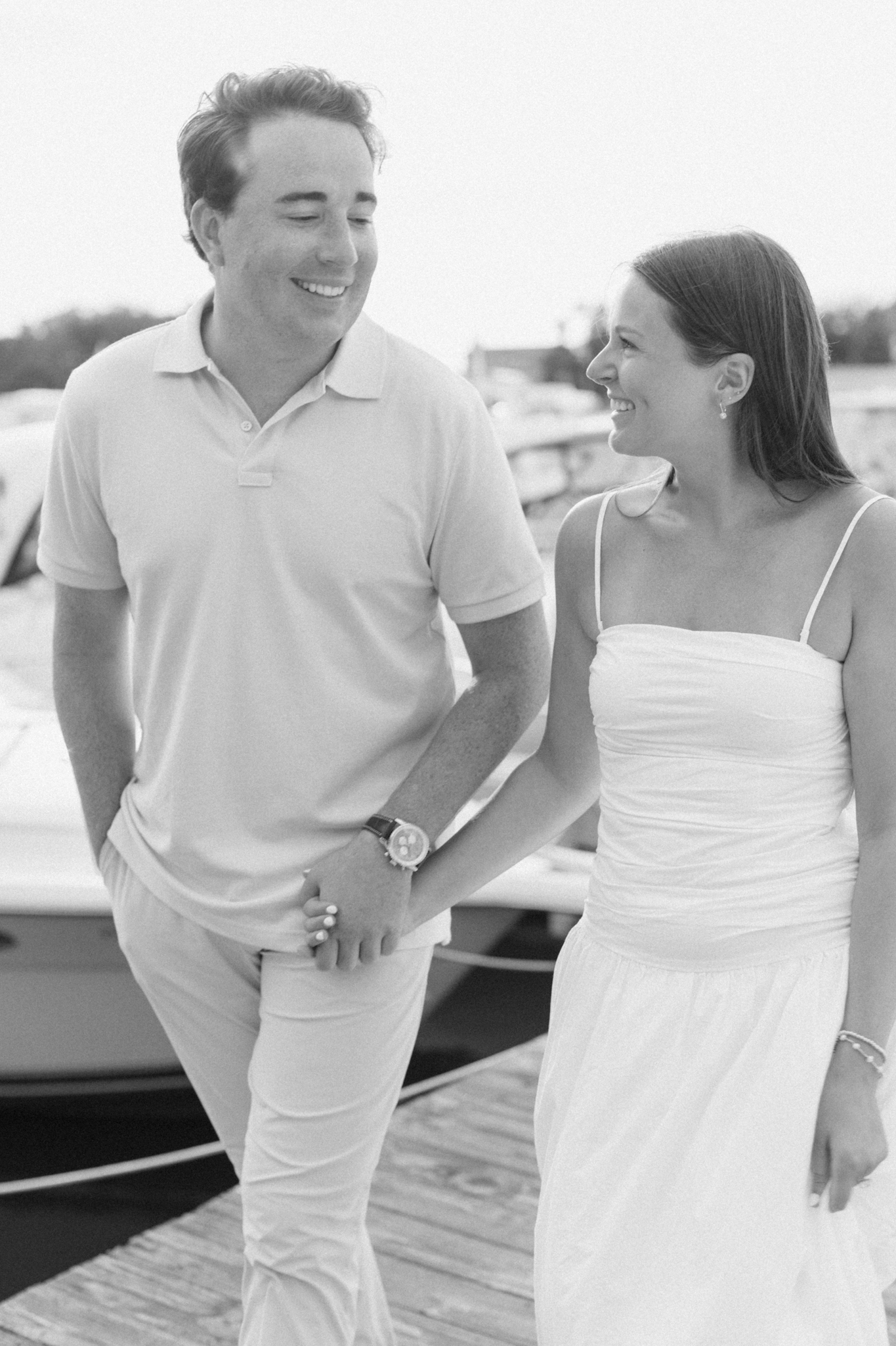 Black and white photo of Lauren and Jason laughing as they walk along the marina dock