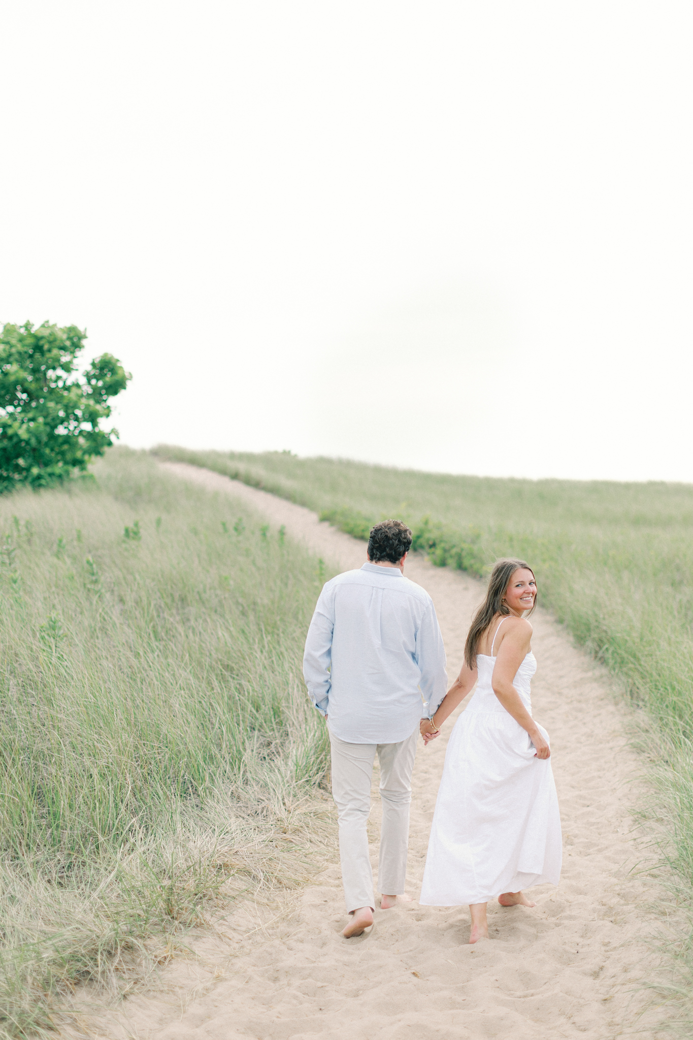 Lauren and Jason walking away from the camera up a grassy dune path