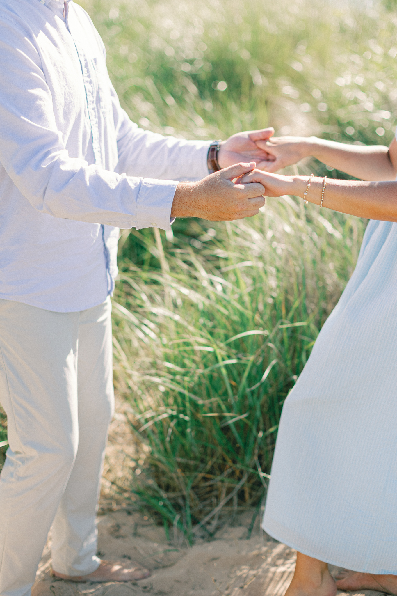 Close-up of Lauren and Jason holding hands in the beach grass