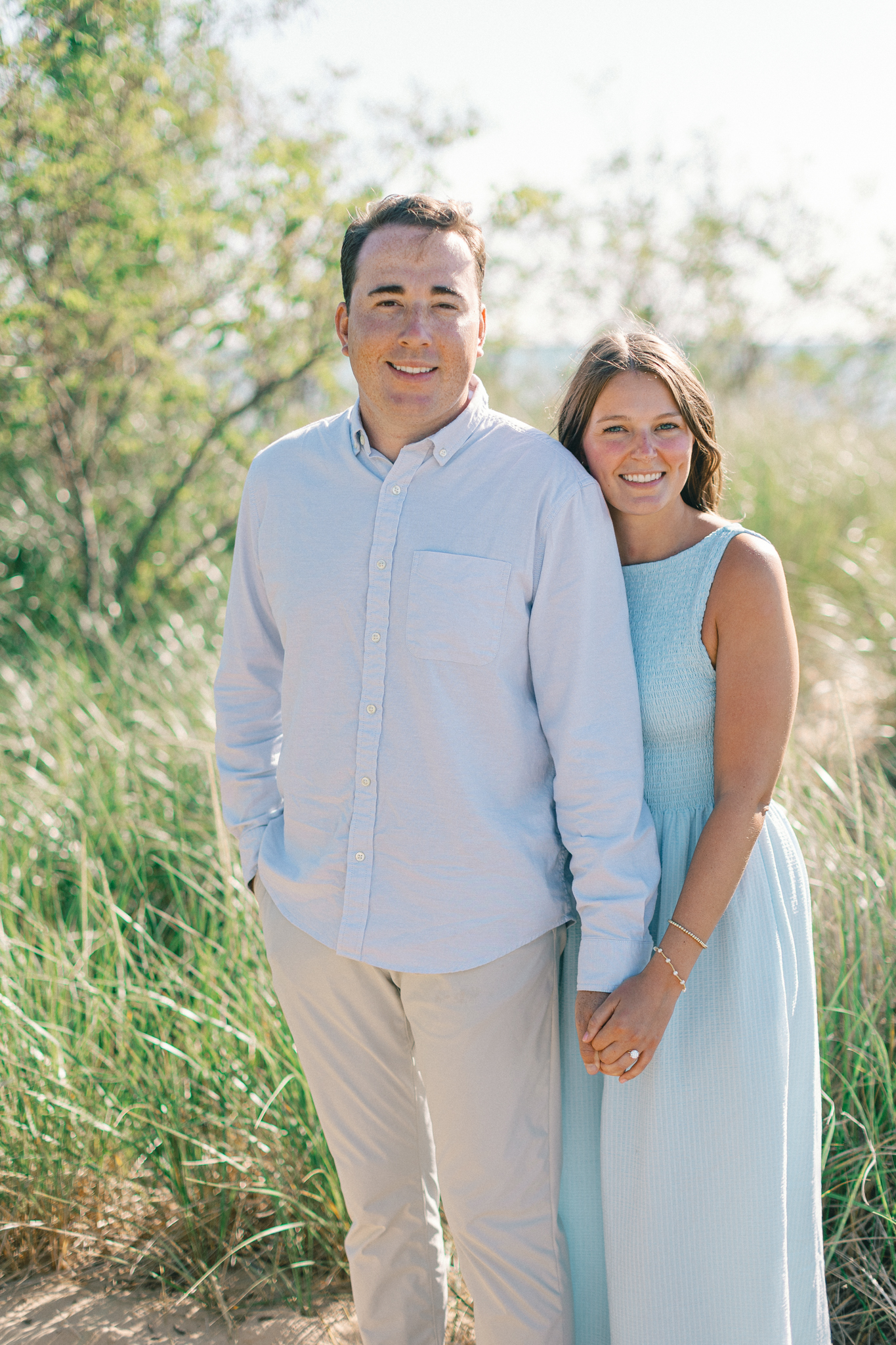 Lauren and Jason smiling at the camera in the dune grass, photographed by a West Michigan wedding photographer