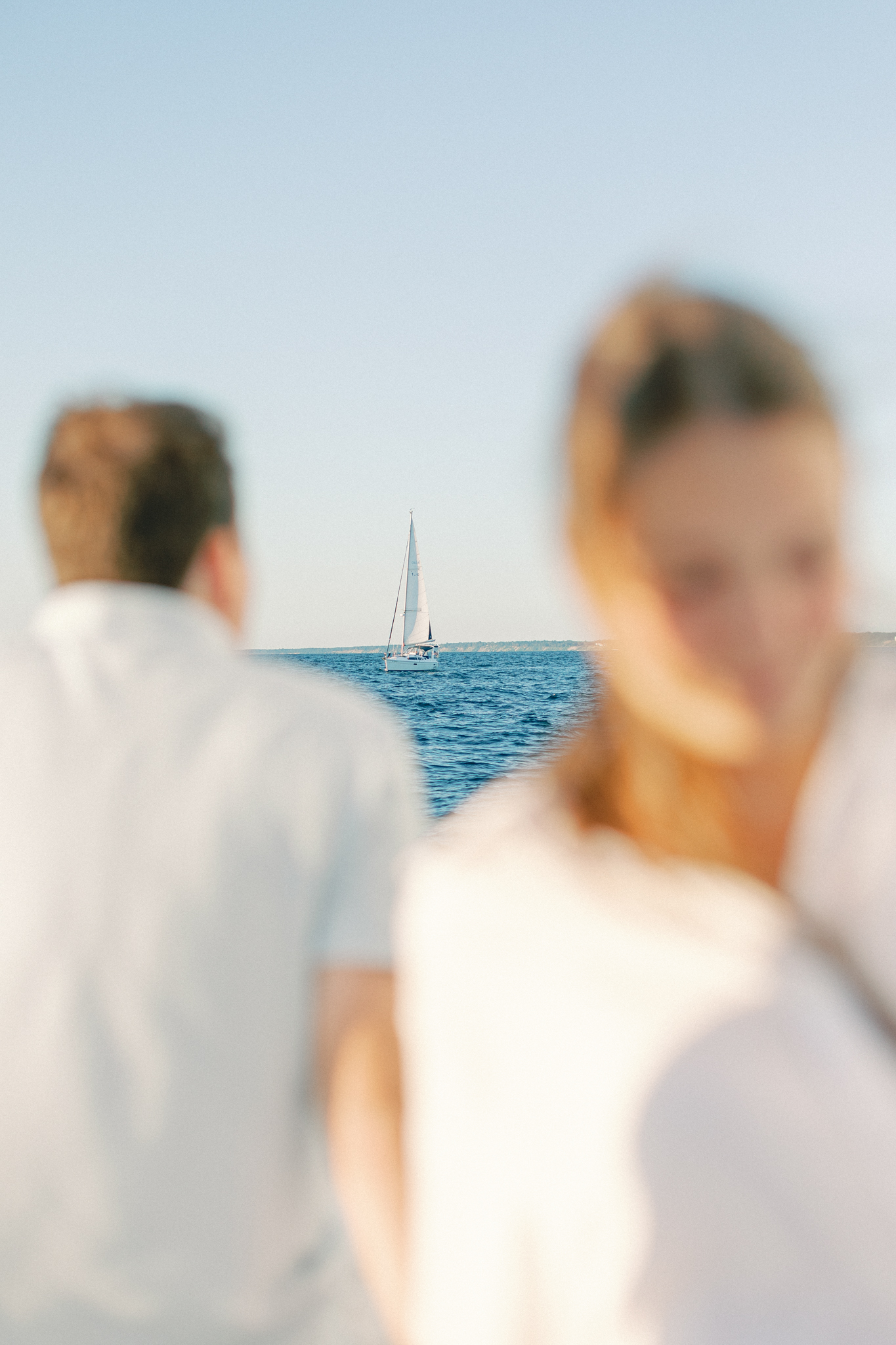 Soft-focus portrait of Lauren and Jason with a sailboat on Lake Michigan in the distance