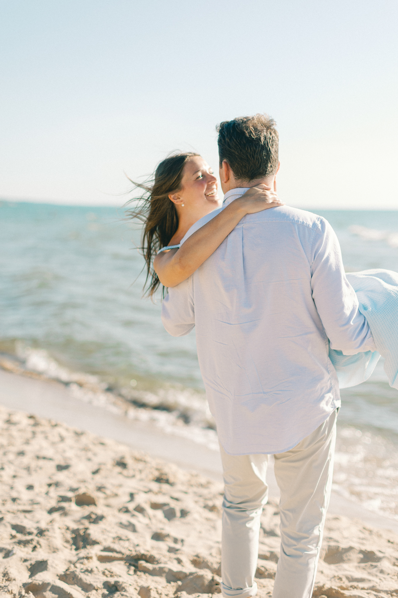 Jason lifting Lauren at the water's edge on a Lake Michigan beach