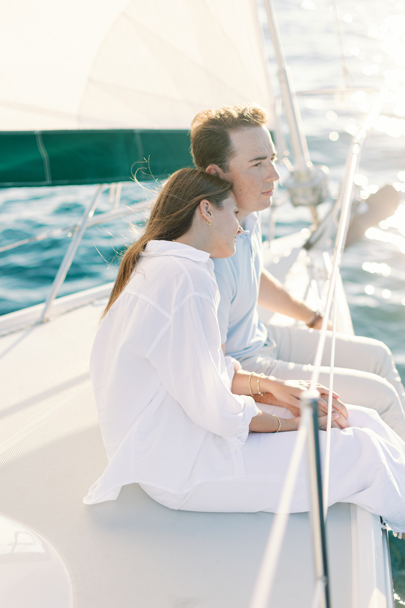 Lauren and Jason sitting on the edge of a sailboat looking out over the water in South Haven, Michigan