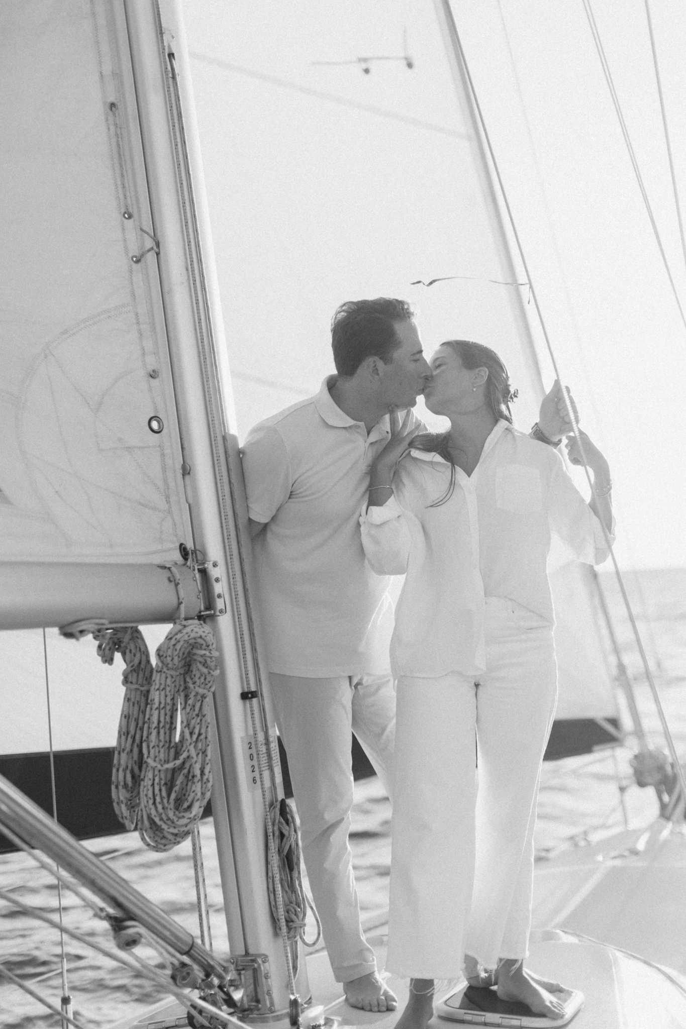 Black and white photo of Lauren and Jason kissing beside the mast of a sailboat on Lake Michigan
