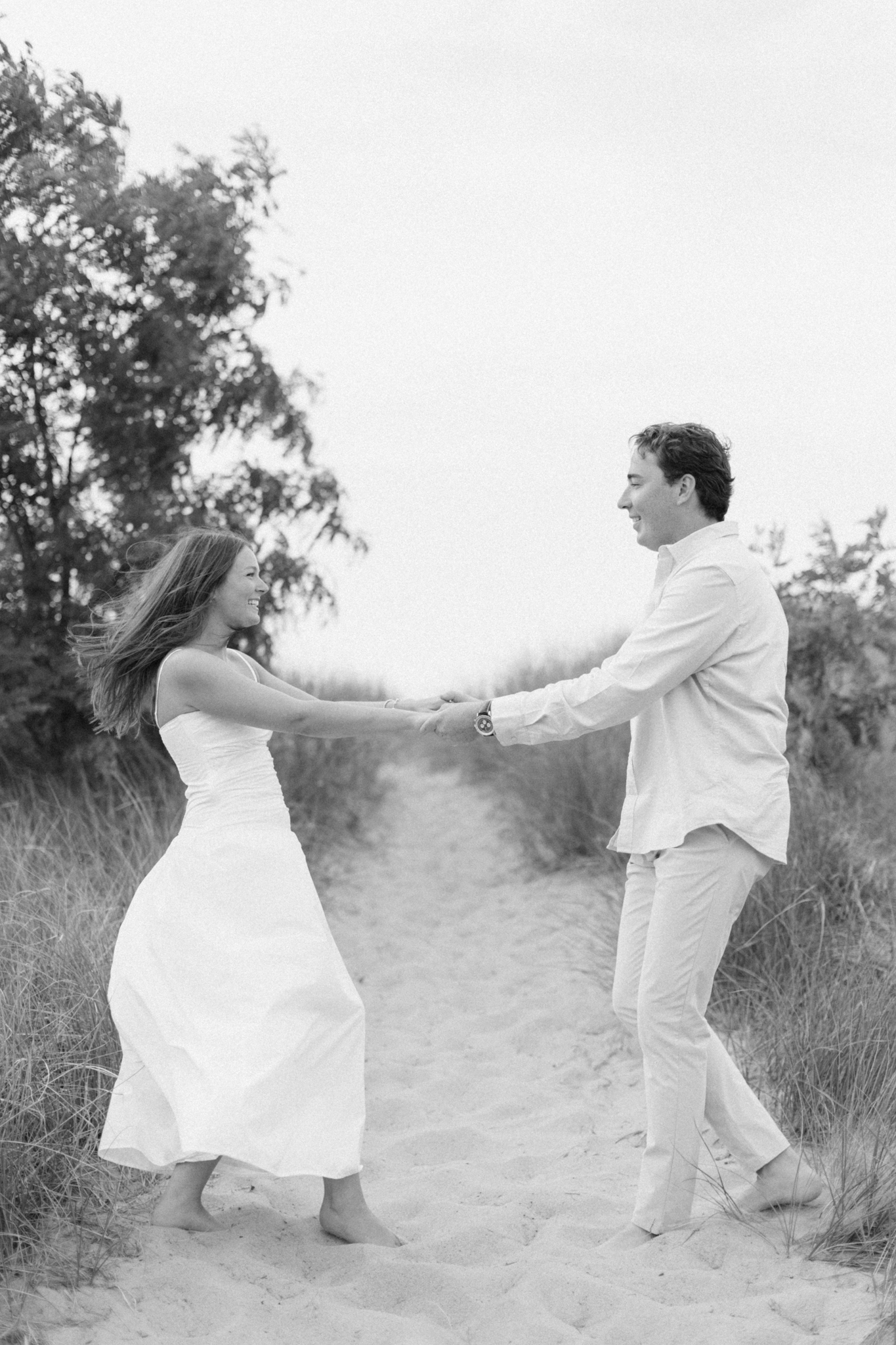Black and white photo of Jason spinning Lauren on a sandy wooded path during their Michigan engagement photos