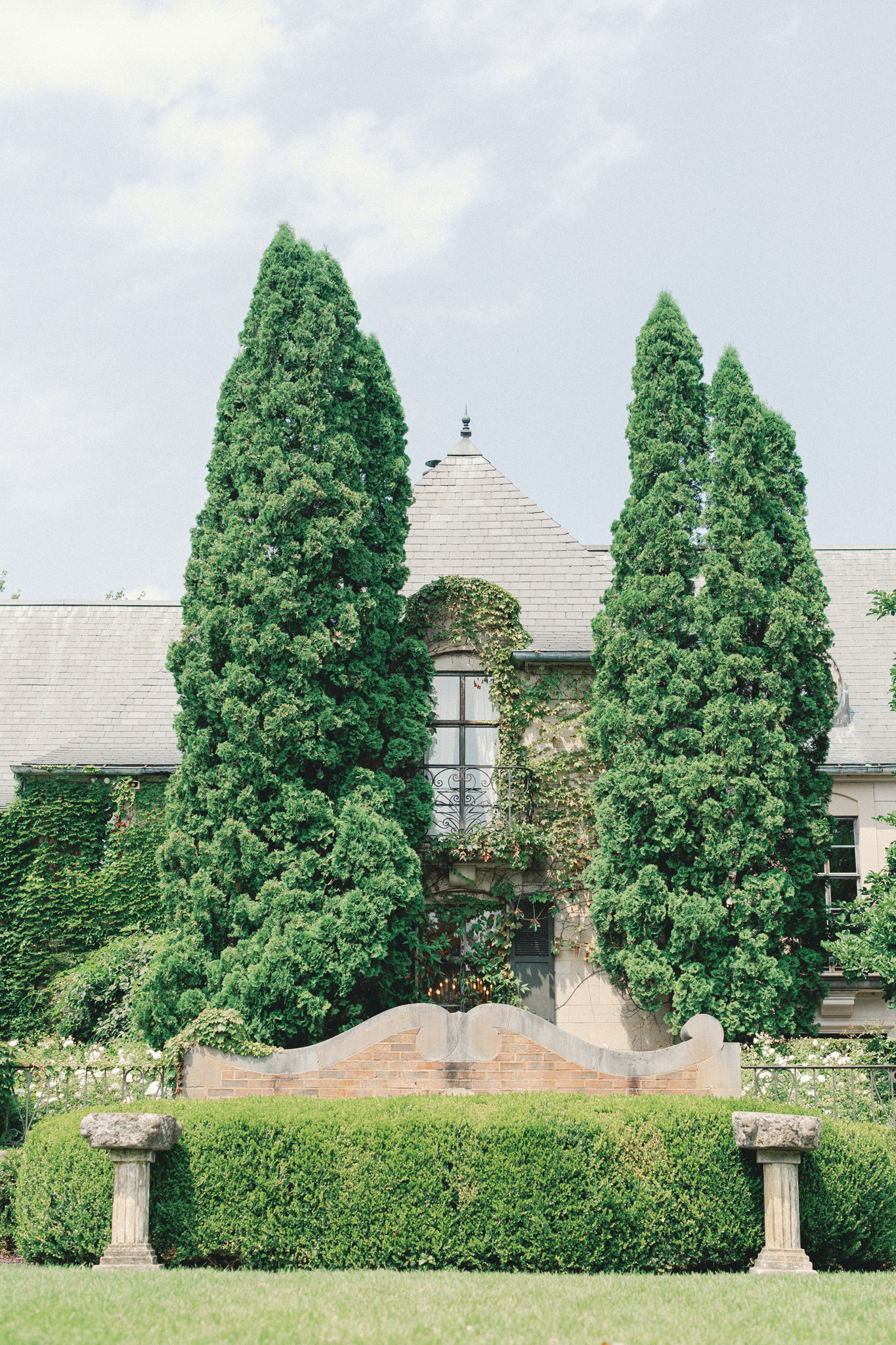 formal garden with cypress trees clipped hedges and stone columns at Greencrest Manor Battle Creek Michigan