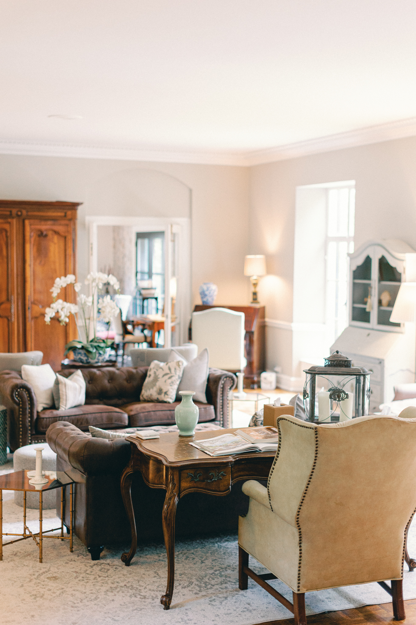 light-filled sitting room with French antiques leather sofa and orchids inside Greencrest Manor Michigan wedding venue