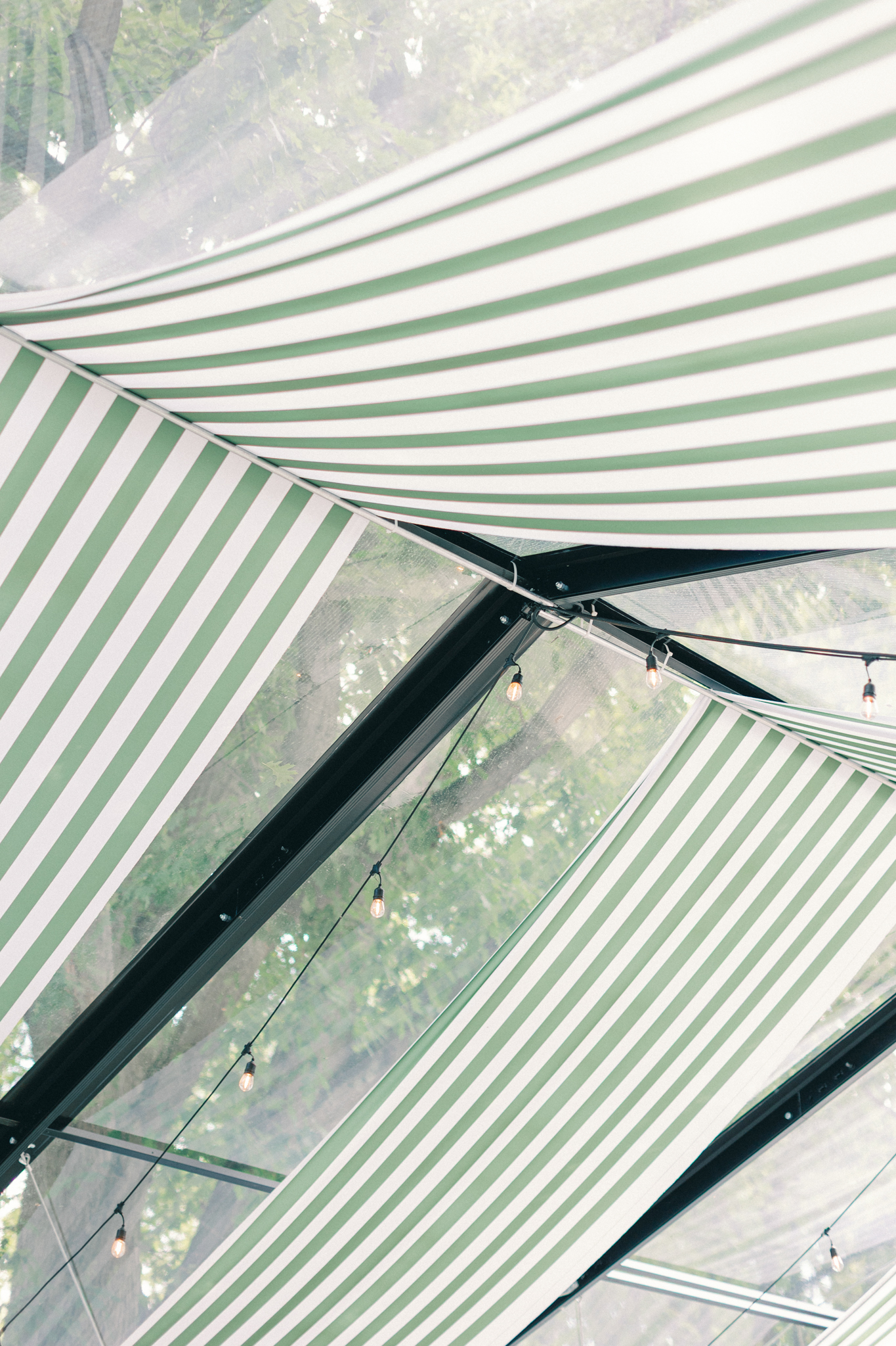 green and white striped canopy with clear panels and string lights at Greencrest Manor Michigan wedding venue