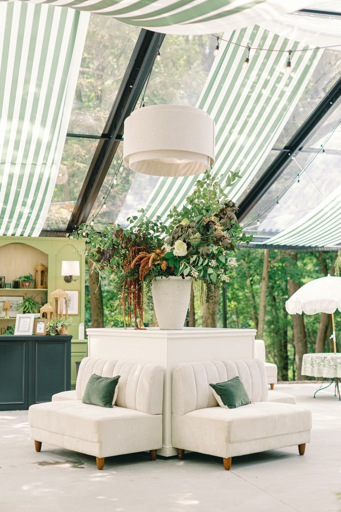 open-air clear structure reception space with lounge seating and statement floral arrangement at Greencrest Manor Michigan wedding